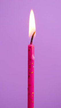 Mor arka planda yanan bir pasta mumu. Yanan pembe ya da morumsu tek pastalı mumu kapat.