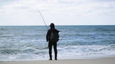 Sakin bulutlu bir günde tek başına okyanusa doğru yol alan balıkçı, dalgaları ve uzak ufku olan huzurlu bir sahil balıkçılığı sahnesi..
