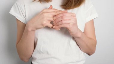 Beyaz tişörtlü genç bir kadın parmağındaki yüzüğü çıkarıyor. Yakın çekim, ayrılığın, boşanmanın ve ilişkinin bitmesine izin vermenin duygusal sembolünü vurguluyor.