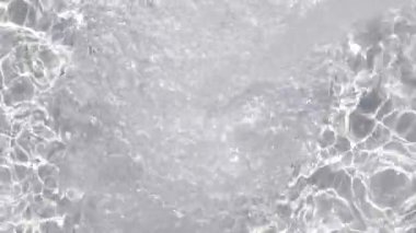 Kabarcık kümeleri ve dans eden yansımalarla köpüren su türbülansı. Parlak ışık koşulları altında canlı bir sıvı enerji ve doku gösterimi