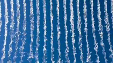 Su akıntılarının parlak mavi gökyüzüne karşı canlı görüntüsü, dinamik, soyut bir şablon yaratıyor doğa veya enerji temalı görseller için ideal.
