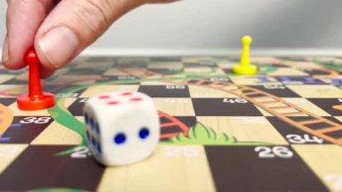 El hareketli kırmızı oyun parçası renkli masa üzerinde zarlar ve sarı piyon. Arkadaş kavramlı masa oyunu zamanı