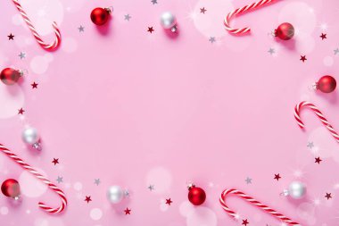 Noel kompozisyonu. Çubuk şekerlerden yapılmış çerçeve, pembe arka planda tatil süslemeleri. Noel, kış, yeni yıl konsepti. Düz konum, üst görünüm, kopyalama alanı