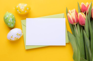 Template for Easter greeting card. Blank card with an envelope, a bouquet of tulips and decorative eggs and a rabbit.