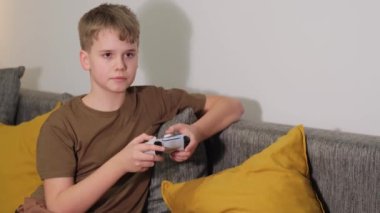 Genç çocuk konsolda video oyunu oynuyor, elleri joystick 'i tutuyor. Evde iyi eğlenceler.