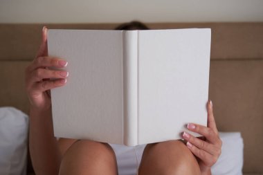 Elinde boş bir defter ya da kitap tasarımı tutan, kapak tasarımını sergileyen genç bir kadın. Kitap maketini aç.