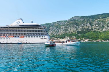 Kotor Körfezi 'nin resimli panoramik manzarası, etrafındaki dağlar ve güneşli bir yaz gününde bir yolcu gemisi. Karadağ, Güney Avrupa. Seyahat kavramı
