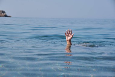 Suda boğulan birinin eli. Yüzme güvenliği kavramı, suya dikkat et.
