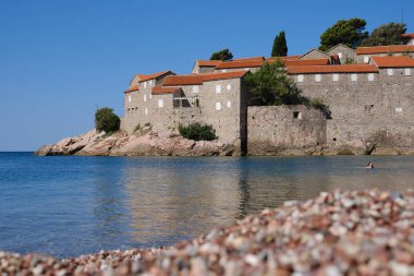 Karadağ 'ın güneşli yaz gününde Sveti Stefan adası yakınlarındaki güzel boş plaj. Adriyatik Denizi, Budva, Karadağ 'daki adada lüks turistik tatil beldesi.