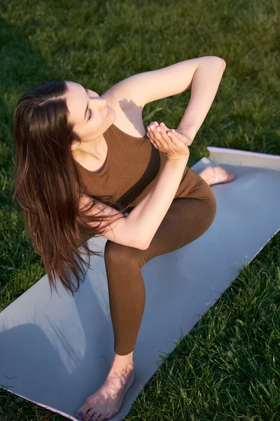 Young woman doing yoga lying on a mat in the park. The concept of a healthy lifestyle and life extension