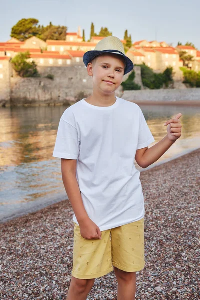 Κομψό Έφηβο Αγόρι Ψάθινο Καπέλο Στην Παραλία Χαμογελάει Και Δείχνει — Φωτογραφία Αρχείου