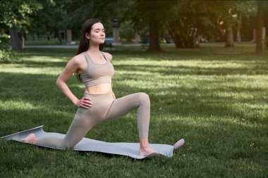 Yoga ya da parkta açık hava sporları yapan genç bir atletik kadın. Sağlıklı yaşam tarzı ve uzatma kavramı.