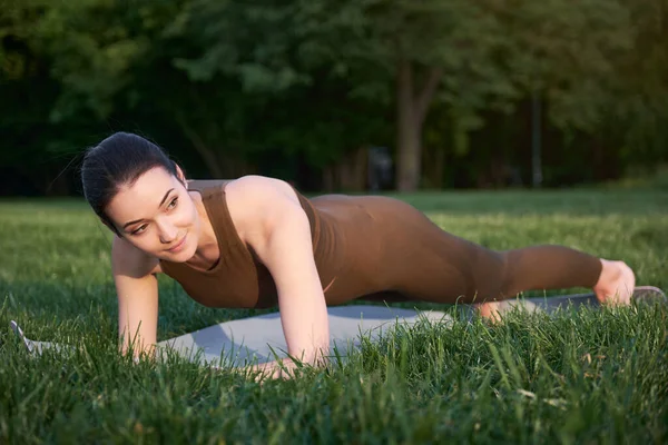 一位年轻美丽的女子 身强体壮 站在公园里做瑜伽 摆出一副木板的姿势 健康生活方式和延长生命的概念 — 图库照片