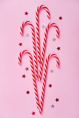 Noel kompozisyonu. Çubuk şekerler, pembe arka planda tatil süslemeleri. Noel, kış, yeni yıl konsepti. Düz yatış, üst görünüm