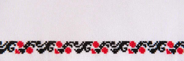 Embroidery design with red and black cotton threads on white linen. Background with embroidery for a banner. Border embroidered with cross stitch technique