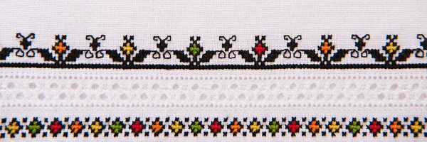 Embroidery design with colored cotton threads on white linen. Background with embroidery for a banner. Cross-stitch and hemstitch technique.