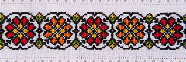 Embroidery design with colored cotton threads on white flax. Background with handmade embroidery for banner.