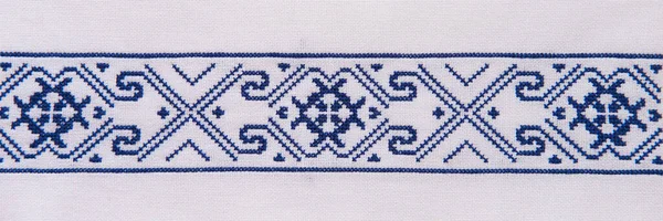 Embroidery design with blue cotton threads on white flax. Background with element handmade embroidery for banner. Geometric ornament.