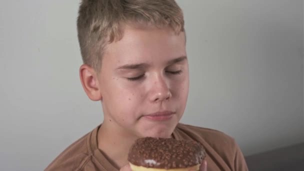 一个少年高兴地吃了一小口巧克力甜甜圈 不健康的甜食 — 图库视频影像