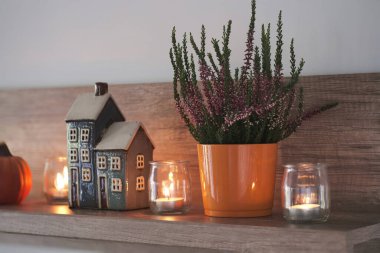 Oturma odasındaki bir rafta sonbahar kompozisyonu. Dekoratif ev, mumlar, fırın ve balkabağı. Sonbahar, sonbahar, ev dekorasyonu..