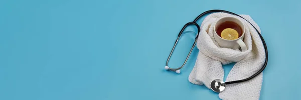 Medical banner with tea, stethoscope and thermometer on a blue background. Healthcare, seasonal flu and treatment concept.