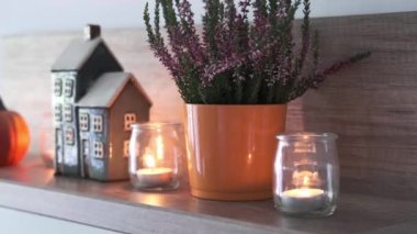 Oturma odasındaki bir rafta sonbahar kompozisyonu. Dekoratif ev, mumlar, fırın ve balkabağı. Hygge ev dekorasyonu için şirin bir sonbahar düzenlemesi.