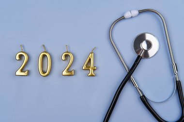 Stetoskop, 2024 numara ve mavi arka planda haplar. Yeni yılda sağlık ve sigorta kavramı.