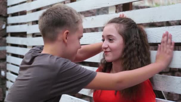 初恋时 一个十几岁的男孩缠着一个女孩 谈论着拥抱着 一个少女害羞地微笑着看着男孩 — 图库视频影像