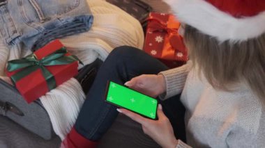 Bir kadın akıllı telefon ve kredi kartı kullanıyor. Başvuru ya da hizmet için bir model. Noel alışverişi ve indirimleri.