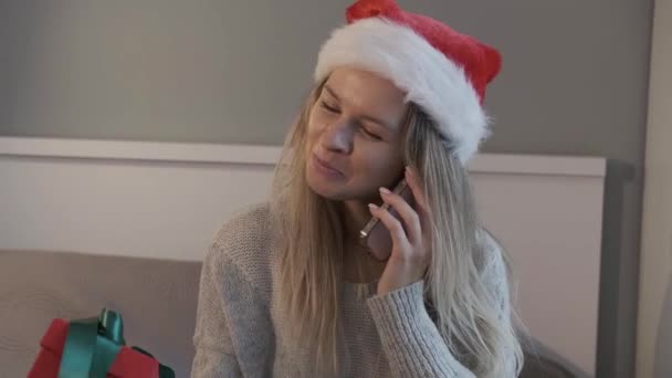 サンタのハッピーな女性は クリスマスプレゼントを持っている間 電話で話すのが大好きです クリスマスショッピングと割引 — ストック動画