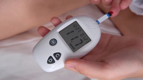 Teenage girl measures blood glucose level on bed at home. Diabetes checking blood sugar level.