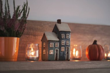 Oturma odasındaki bir rafta sonbahar kompozisyonu. Dekoratif ev, mumlar, fırın ve balkabağı. Hygge ev dekorasyonu için şirin bir sonbahar düzenlemesi.