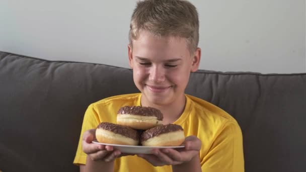 Голодний Хлопчик Лиже Губи Посміхається Дивлячись Смачні Шоколадні Пончики Концепція — стокове відео