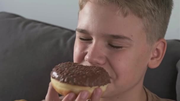 Подросток Удовольствием Откусывает Шоколадный Пончик Нездоровая Сладкая Еда — стоковое видео