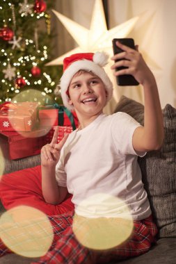 Genç bir blogcu Noel ağacının yanında Noel Baba şapkası takarak bir internet deresi yönetiyor..