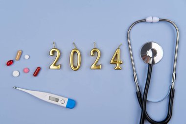 Stetoskop, 2024 numara ve mavi arka planda haplar. Yeni yılda sağlık ve sigorta kavramı.