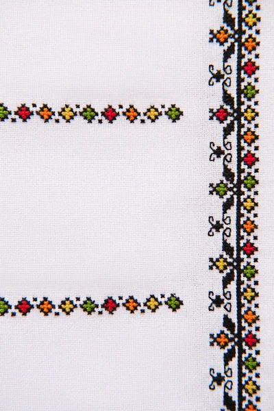 Element of Handmade Embroidery on White Linen by colored Cotton Threads. Craft embroidery. Design of ethnic pattern.