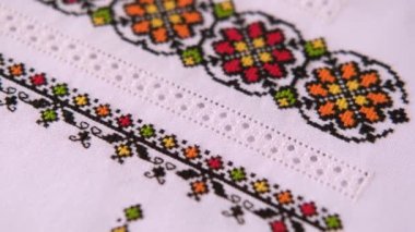 İşlemeli keten beyazı kumaş dokusu. Renkli ipliklerle çapraz dikişler ve ustalıkla dikişler. Halk gömleği için Ukrayna nakış deseni.