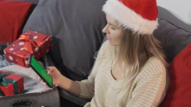 Noel Baba şapkalı bir kadın Noel alışverişi için akıllı telefon kullanır. Noel alışverişi ve indirimleri.