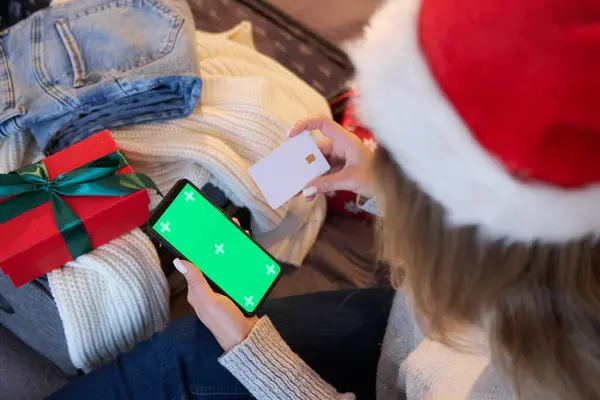Bir kadın akıllı telefon ve kredi kartı kullanıyor. Başvuru ya da hizmet için bir model. Noel alışverişi ve indirimleri.