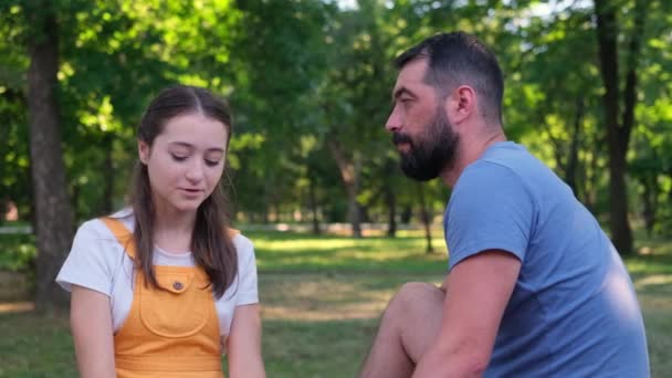 Бородатый Отец Общается Своей Дочерью Подростком Обнимает Сидя Парке — стоковое видео
