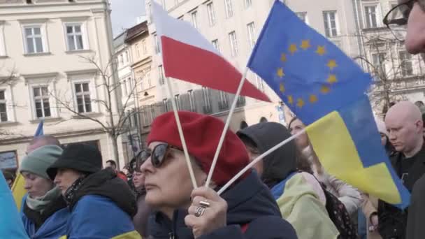 克拉科夫 2024年2月24日 在纪念俄罗斯全面入侵乌克兰周年的集会上 一名妇女举着乌克兰 波兰和欧盟的国旗 — 图库视频影像