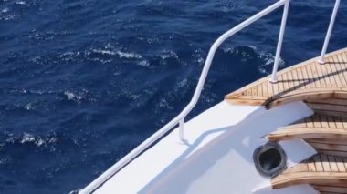Tekne güvertesi köşesinde, derin mavi deniz manzarasına karşı ahşap detaylar..