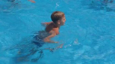 Çocuk havuzda yüzüyor, su sıçramalarına odaklanıyor..