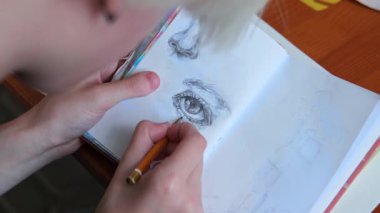 Yetenekli genç bir sanatçı bir defter çizer. Bir göz kapağının kalem çizimi.