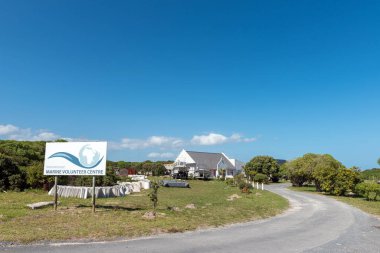 Gansbaai, Güney Afrika - 20 Şubat 2022: Batı Cape Eyaleti 'ndeki Gansbaai yakınlarında Kleinbaai' deki Uluslararası Deniz Gönüllüleri Merkezi 'ne giriş. Tekneler görünür.