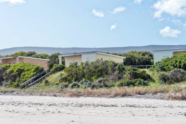 Gansbaai, Güney Afrika - 20 Sep 2022: Batı Burnu 'ndaki Gansbaai yakınlarında Franskraalstrand' daki Uilenkraalsmond 'da Chalets. Göl kenarındaki sahile giden adımlar görülebilir.