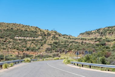 Orange River 'daki Vanderkloof Barajı' nın barajına giden yol. Barajın adı tepenin yamacında görünüyor.