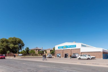 Kakamas, Güney Afrika - 25 Şubat 2023: Kuzey Cape Eyaleti 'ndeki Kakamas' ta bir hırdavatçı, okul, insan ve araç ile sokak sahnesi.