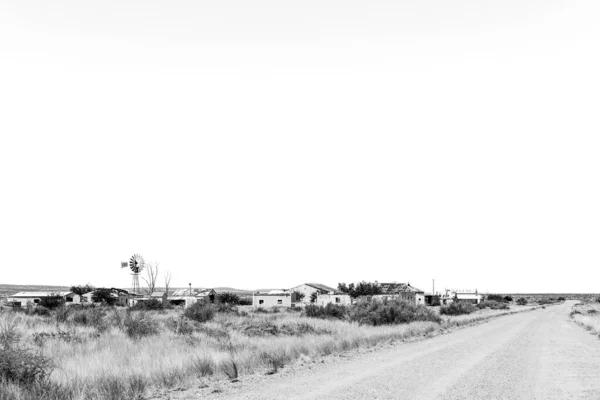 南アフリカのプッソンダーウォーター 2023年2月28日 ケープ州北部のゴーストタウンであるプッソンダーウォーターにある古い建物や遺跡 風車が見える モノクローム — ストック写真